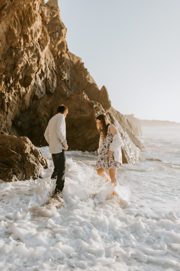 couple playing in the water at the California beach in Big Sur