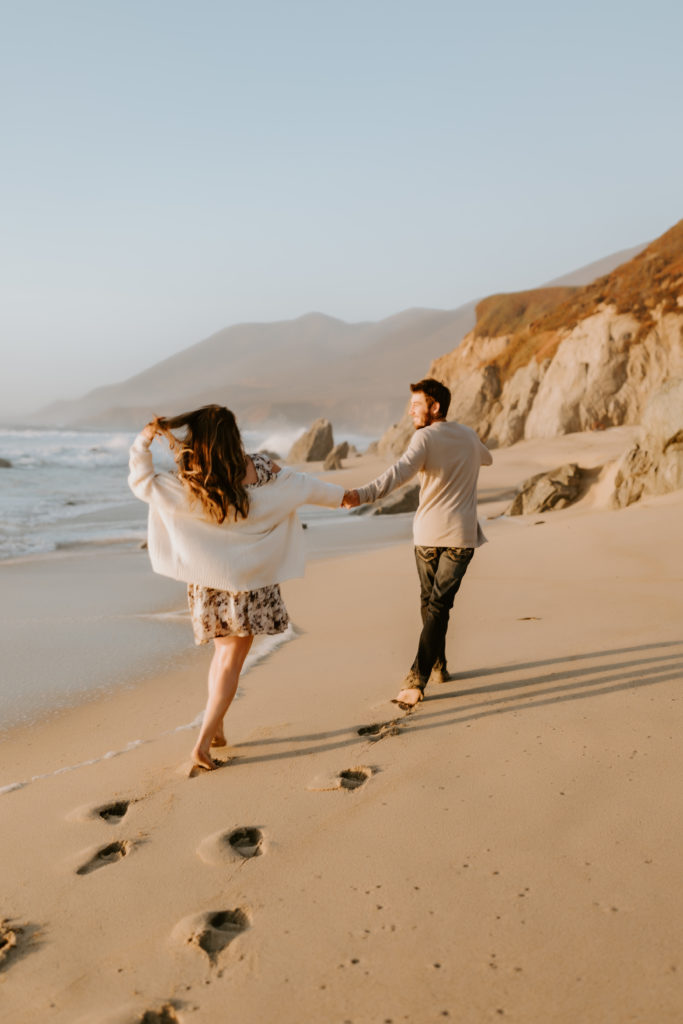 couple running holding hands at the California beach in Big Sur