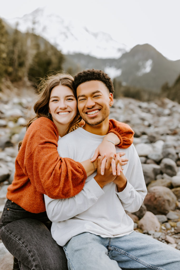girl holding a guy from behind both smiling