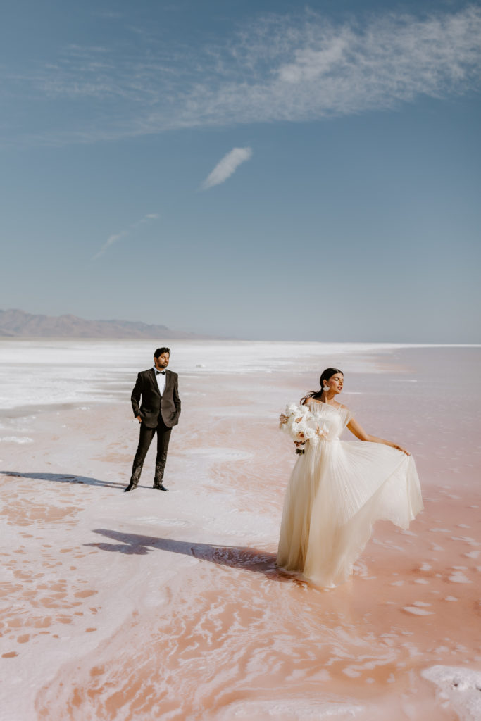 Wedding couple in standing in the pink lake with the mountains view 