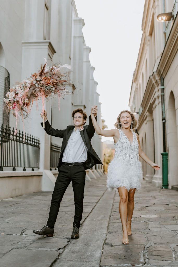 couple smiling in Great Gatsby inspired clothes running on the streets of NOLA