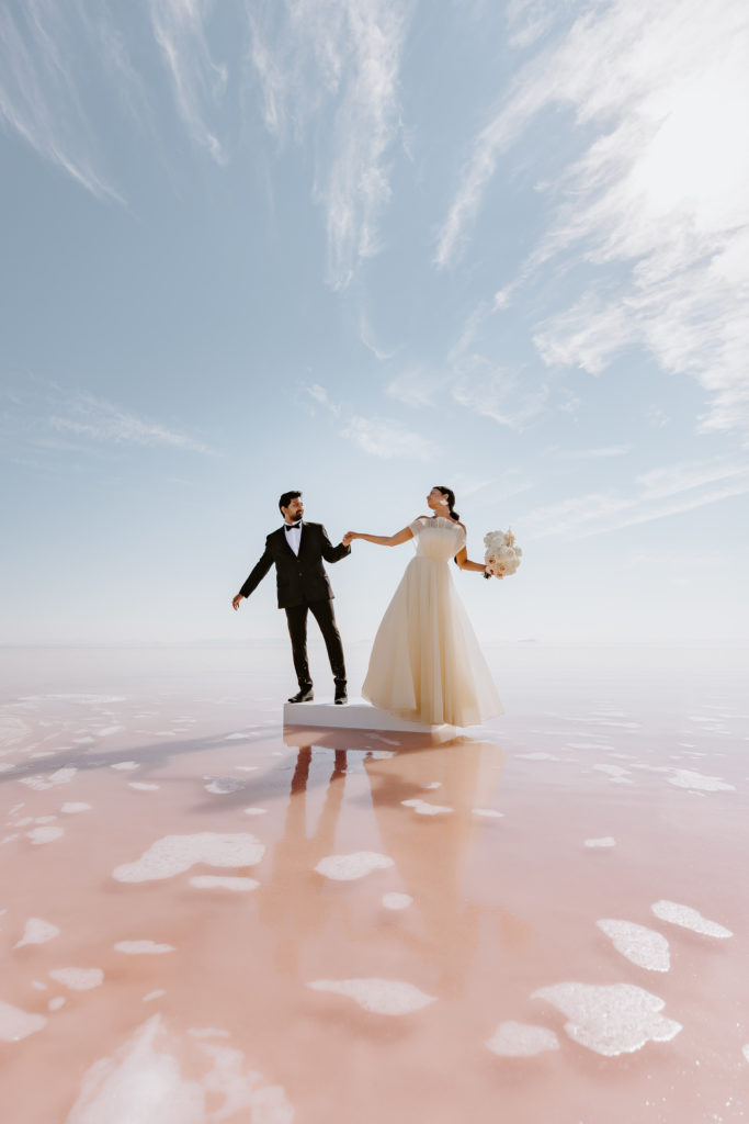couple holding hands in the pink lake in Utah