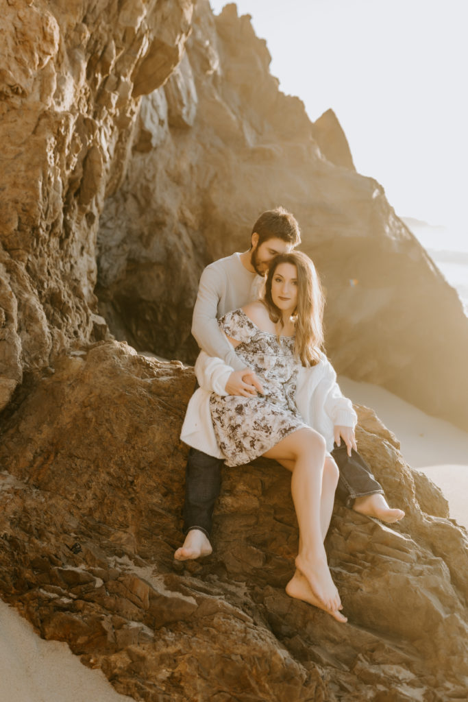 couple sitting on the rock at the California beach in Big Sur