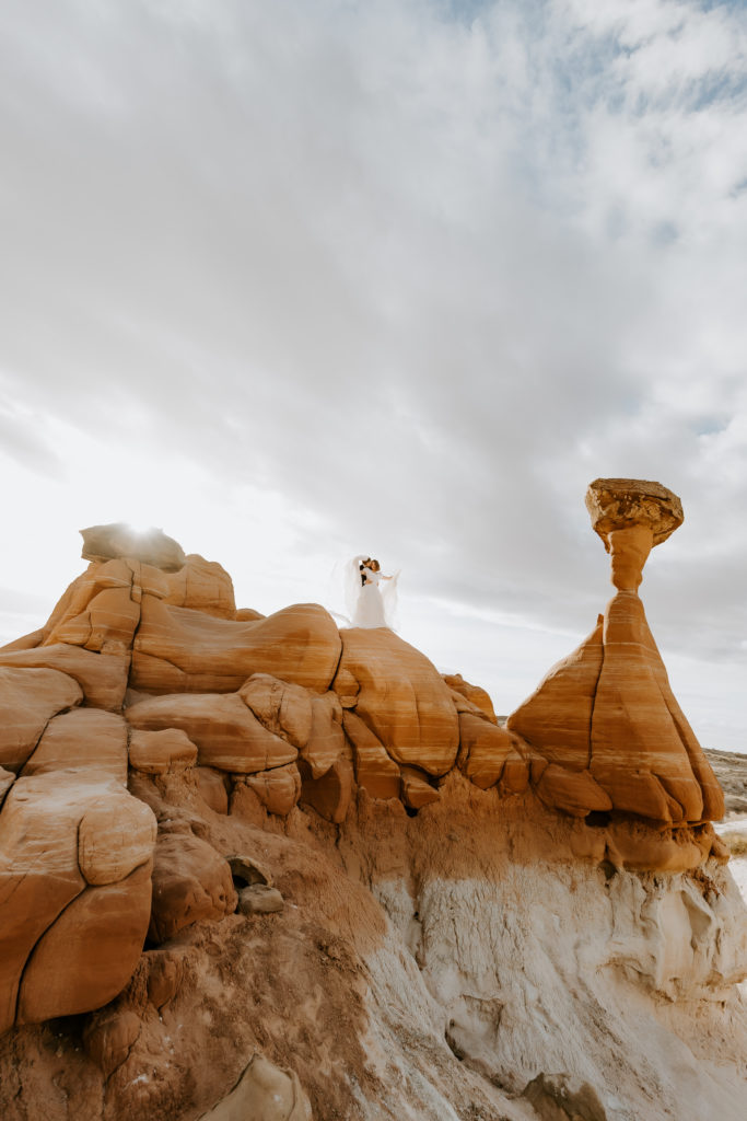 Wedding couple holding hands standing on the Toadstools in Utah