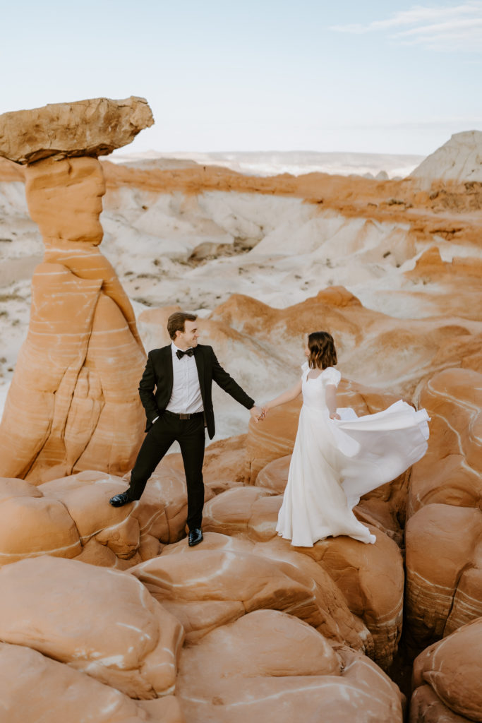Wedding couple holding hands standing on the Toadstools in Utah