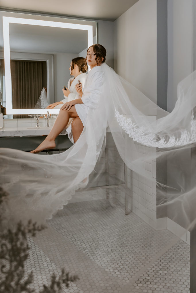 Bride sitting in front of the mirror with the long veil