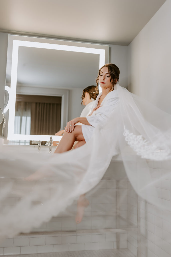 Bride sitting in front of the mirror with the long veil