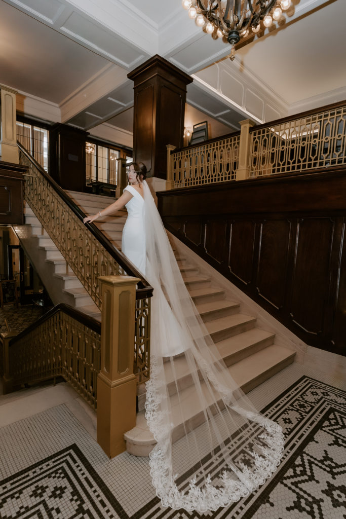 Bride is standing on the stairs with the long veil at The Hotel Northland, Green Bay