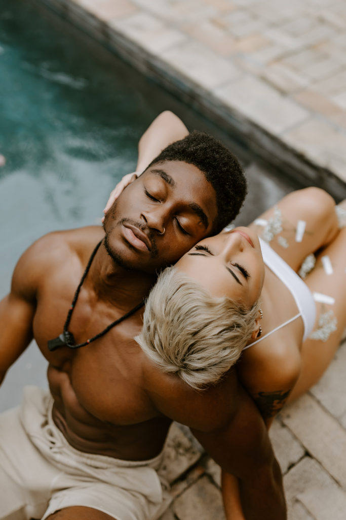 black couple sitting back to back by the pool